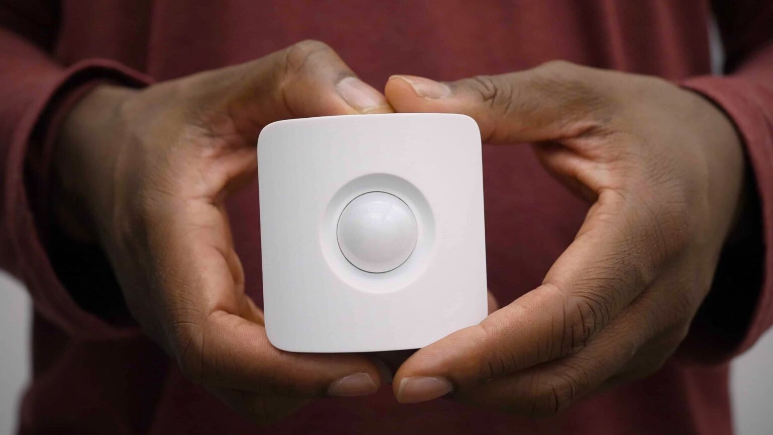 A man is holding a motion sensor alarm system in his hands