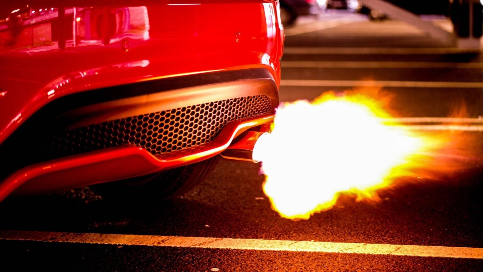 A red car with performance exhaust system emitting fire